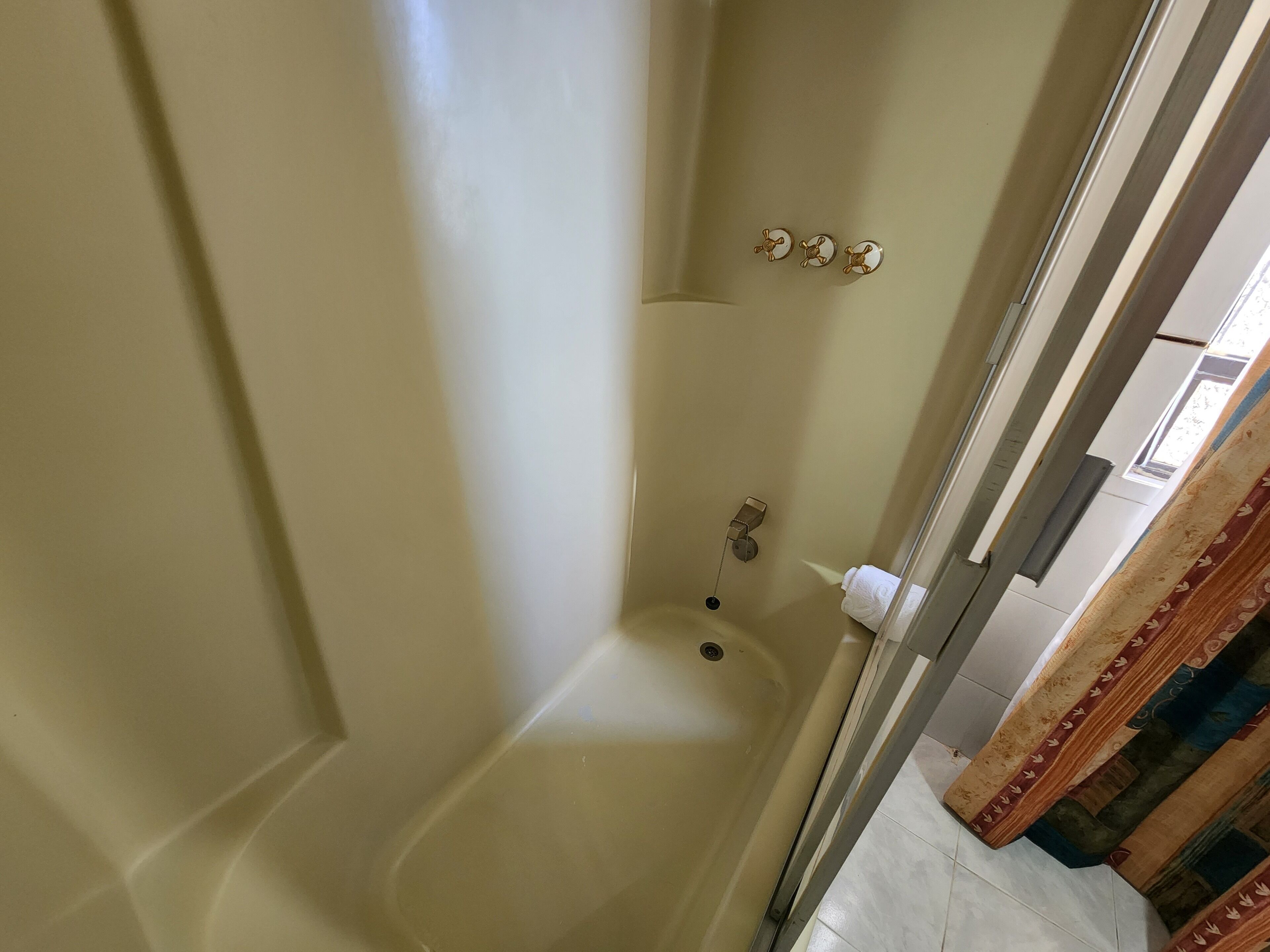A corner of a room with a bathtub, a towel rack, and a window.