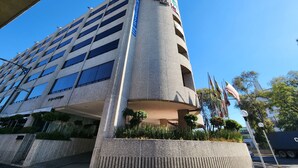 Um edifício de vários andares com uma seção cilíndrica, janelas amplas e uma placa indicando um hotel.