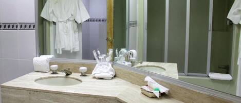 Un baño con lavabo, espejo y artículos de aseo.