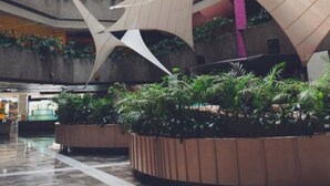 Um átrio de vários níveis com design moderno, apresentando um espaço central aberto com estruturas geométricas e vegetação nas paredes.