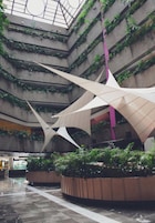 Un atrium à plusieurs niveaux, doté d’un design moderne, avec un espace central ouvert agrémenté de structures géométriques et de verdure sur les murs.