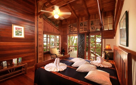 A wooden room with a bed, a chair, and a table.