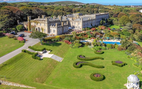 A large, historic building with a formal garden, a swimming pool, and a gazebo.