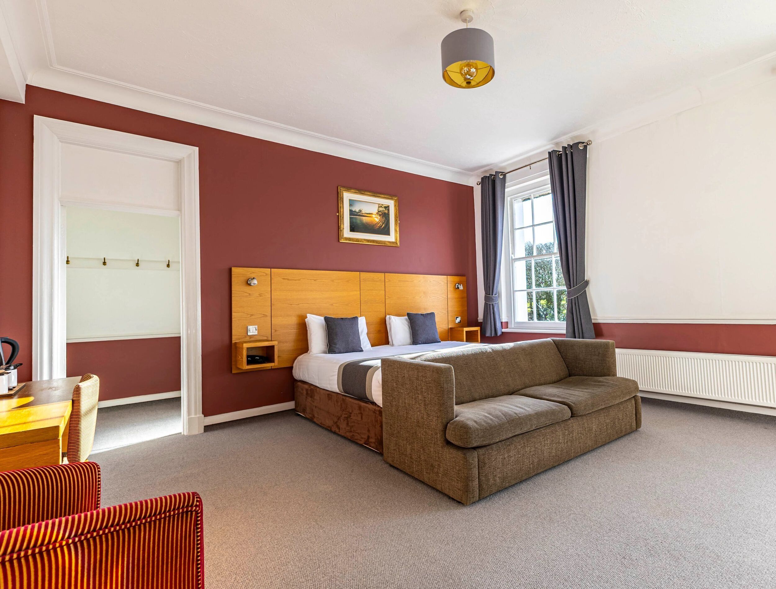 Une chambre d’hôtel avec un lit, un canapé, une petite table et une fenêtre avec des rideaux.