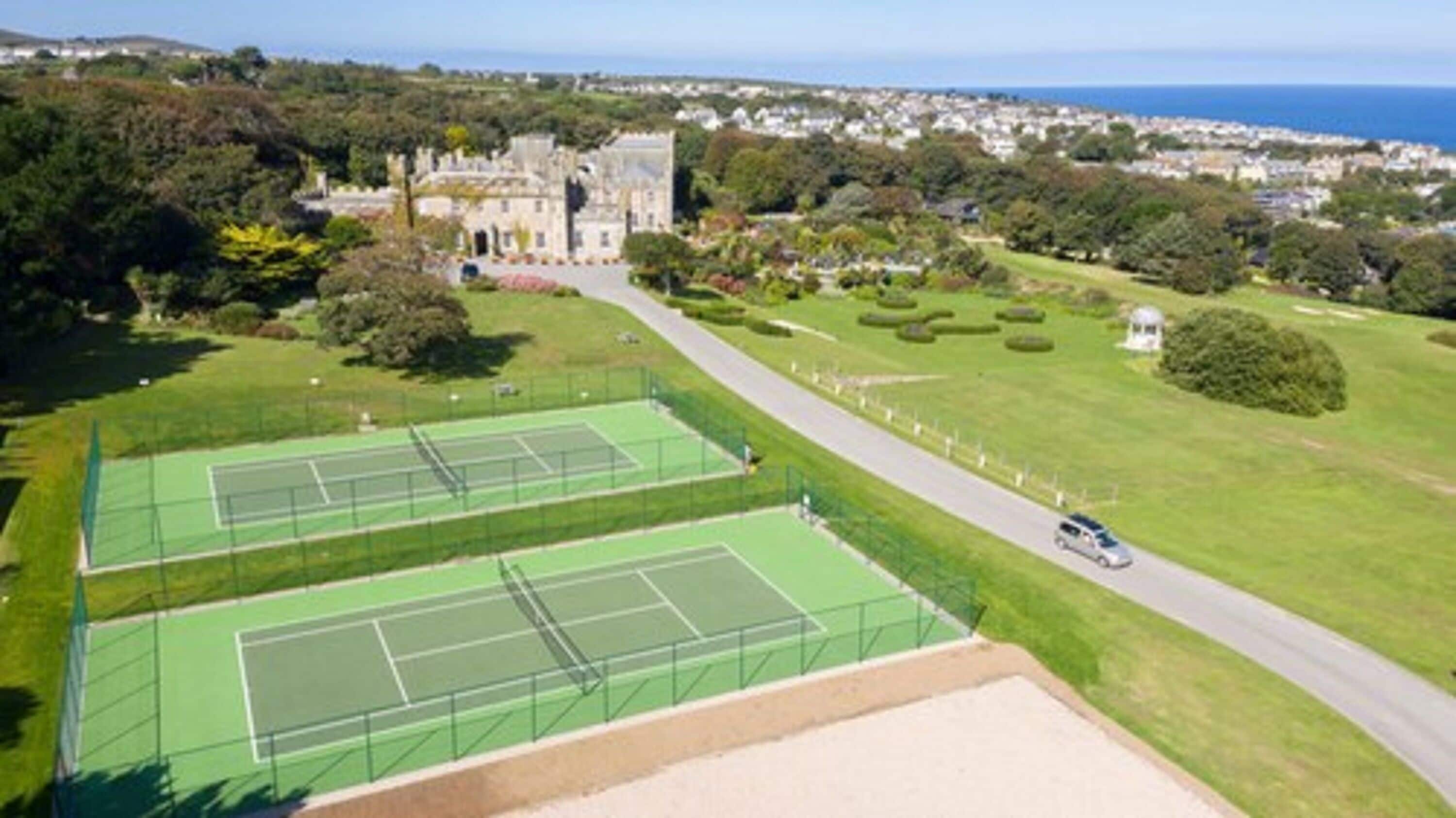 Un complejo de canchas de tenis con un edificio grande al fondo.