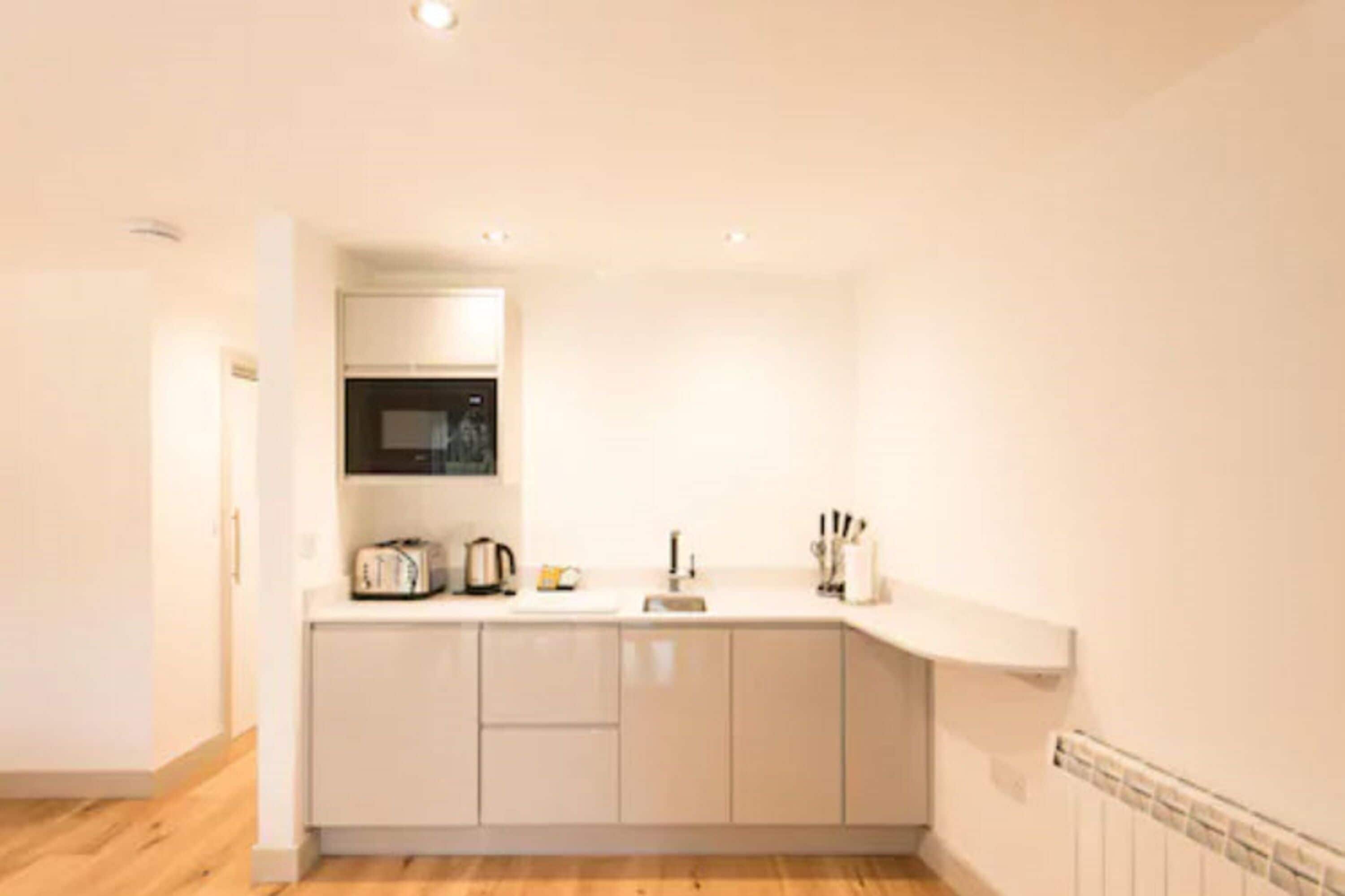 A compact kitchen with a microwave, toaster, and sink.