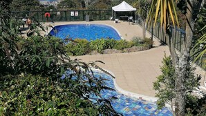 Une piscine avec vue sur l’océan, entourée de verdure et agrémentée d’un belvédère blanc.