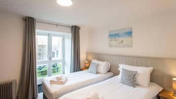 A hotel room with two beds, a painting on the wall, and a view of an outdoor area.