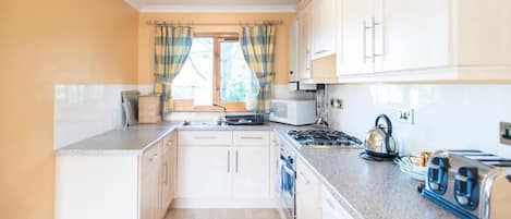 A compact kitchen with white cabinets, a gas stove, a microwave, and a toaster.