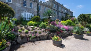 Un bâtiment historique en pierre, avec un jardin à l’avant.