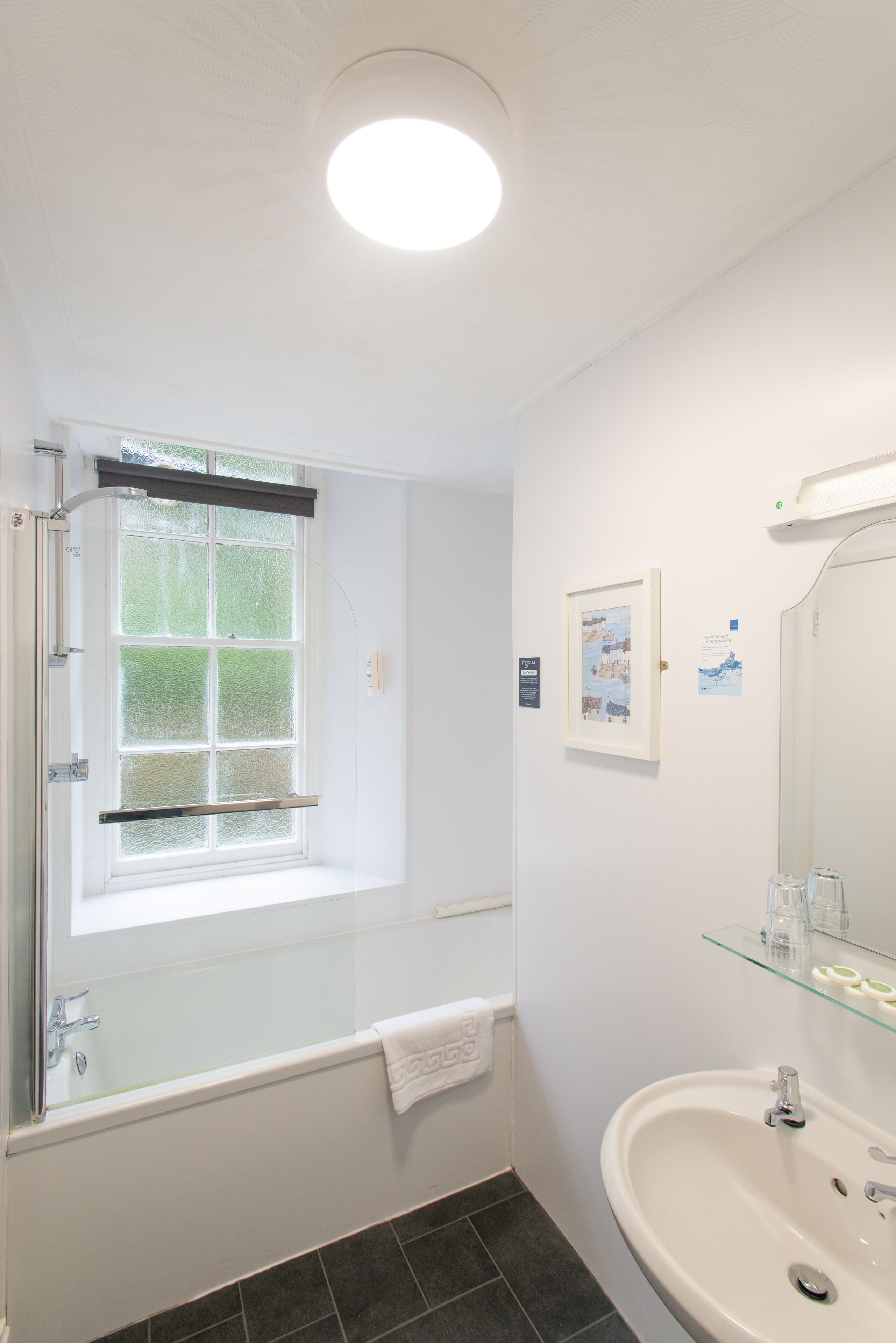 Une salle de bain avec une baignoire, un lavabo, un miroir et une fenêtre.