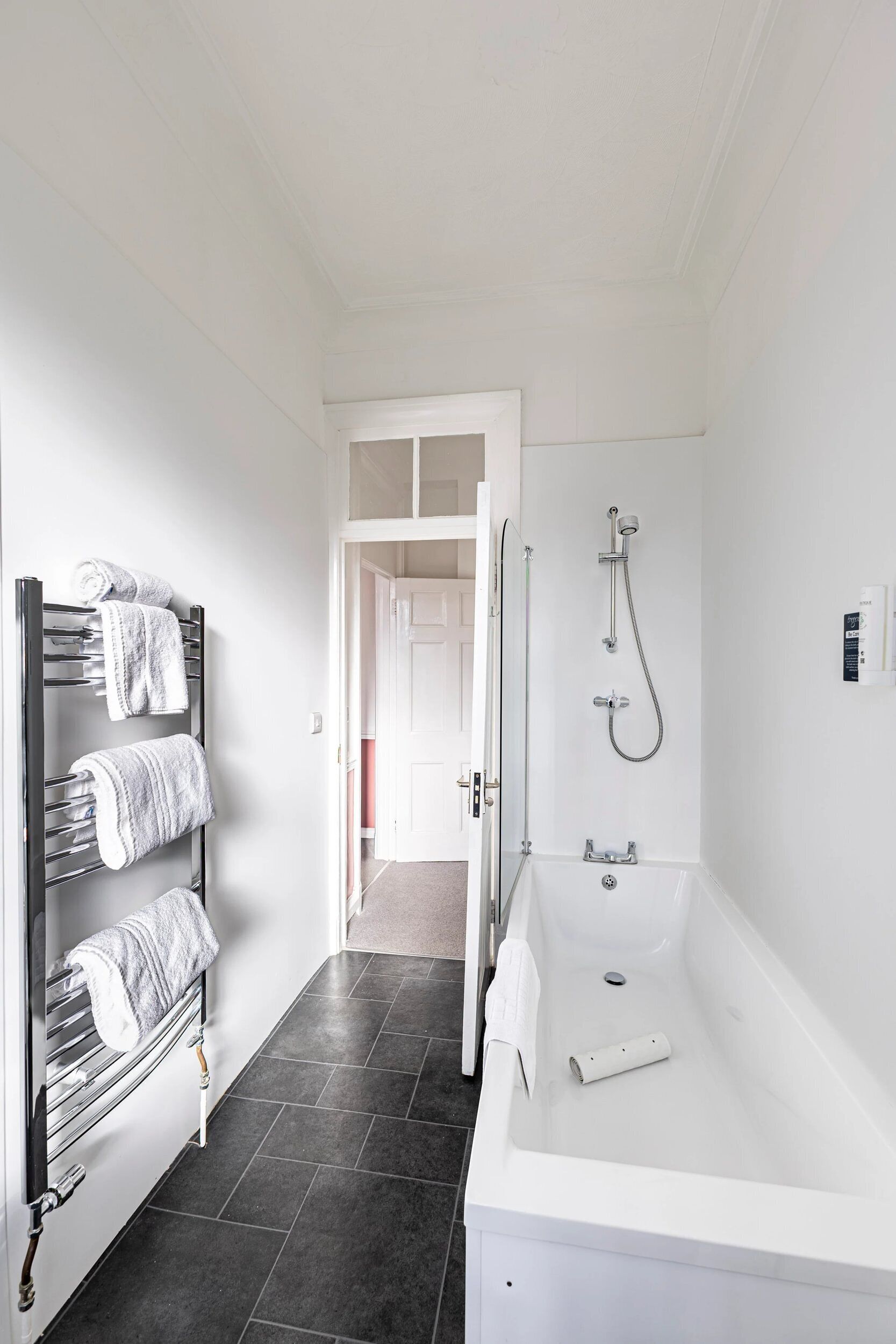 A modern bathroom with a white bathtub, a towel rack with neatly folded towels, and a shower head.