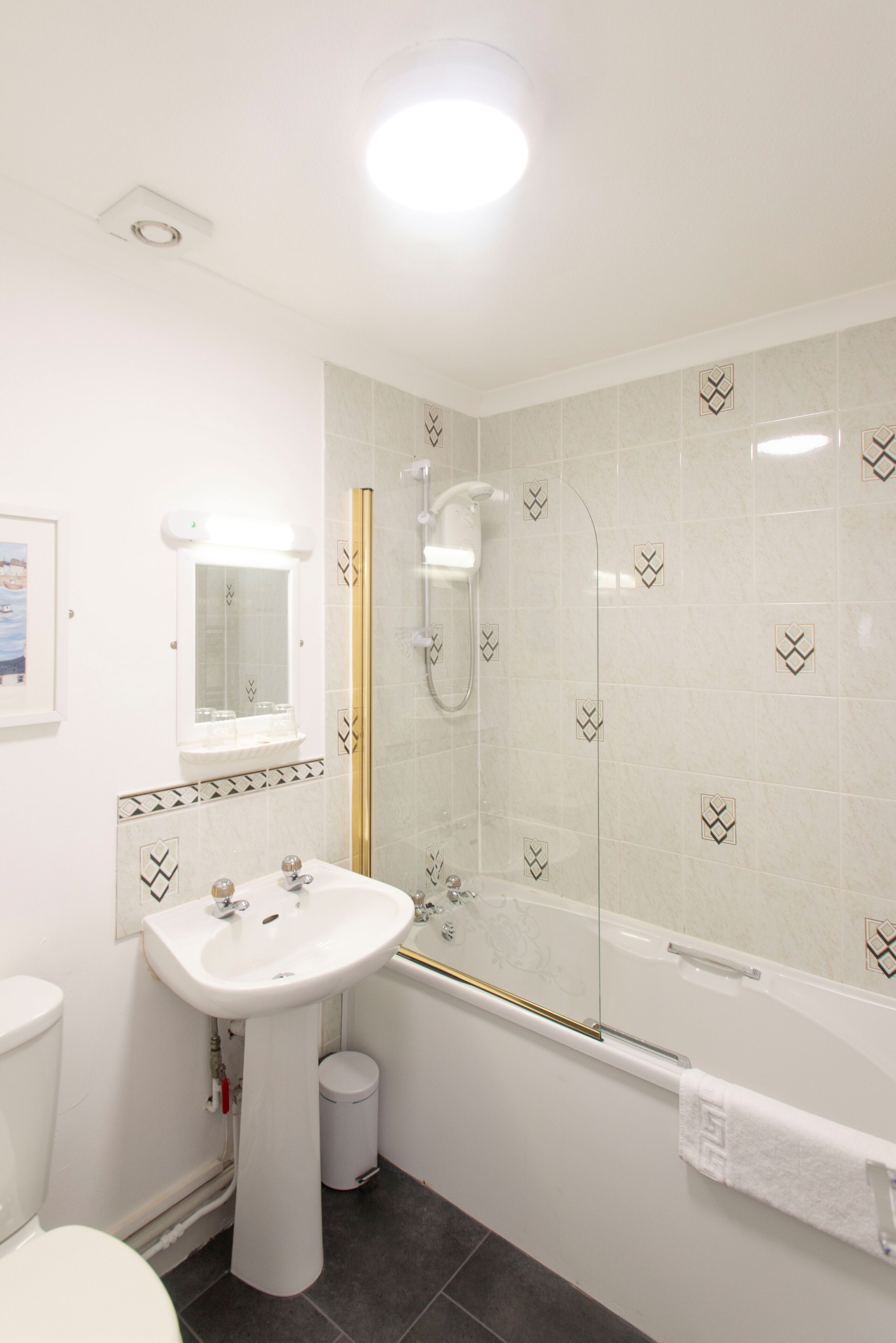 A modern bathroom with a white sink, mirror, and shower.