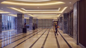 Eine moderne Hotelhalle mit einem polierten Marmorboden, einer großen Rezeption und einer Wand mit dekorativem Muster.