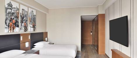A hotel room with two beds, a large TV, and artwork on the wall.