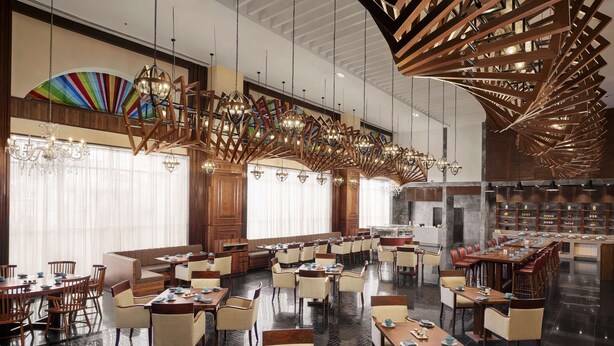 Ein geräumiges Restaurant mit hohen Decken, modernen Kronleuchtern und verschiedenen Sitzmöglichkeiten, darunter runde Tische und gemütliche Sitzecken.