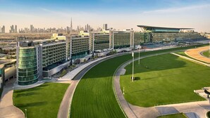 A modern hotel complex with multiple buildings, a central courtyard, and a racetrack. - The Meydan Hotel (Dubai)