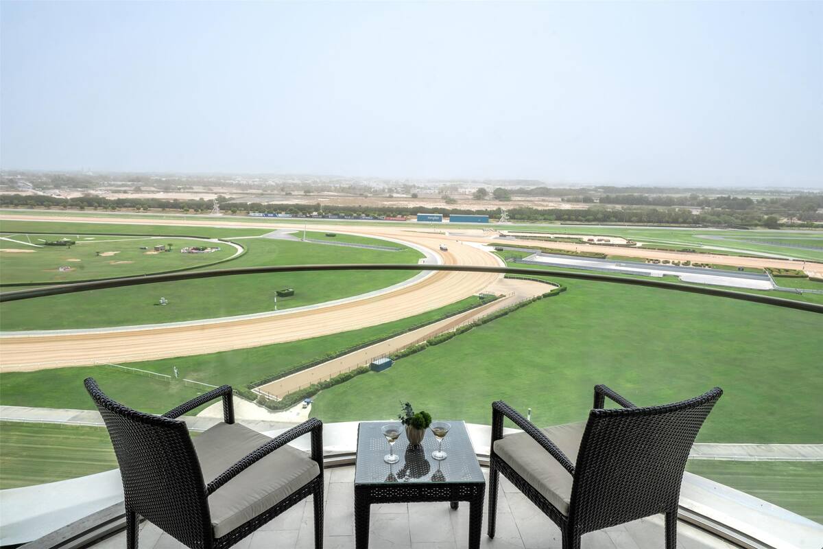 A balcony with wicker furniture overlooking a race track.