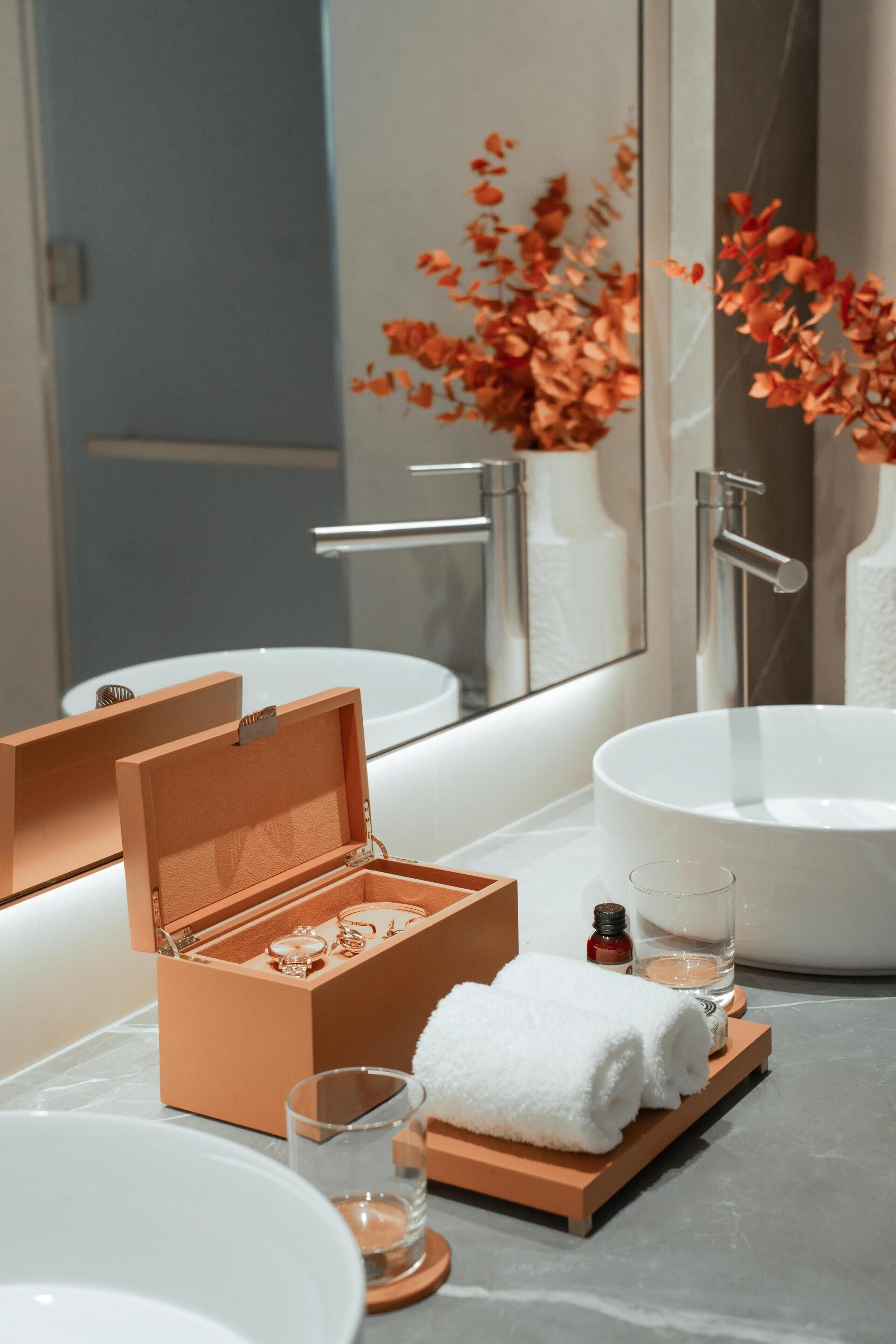 A modern bathroom with a large white sink, a mirror, and a wooden box with a glass.