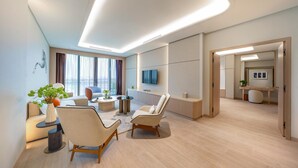 A modern living room with a sofa, two armchairs, a coffee table, and a TV mounted on the wall. - The Meydan Hotel (Dubai)