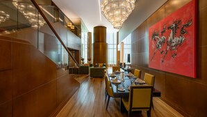 A modern dining area with a long table, chairs, and a large abstract painting on the wall. - The Meydan Hotel (Dubai)