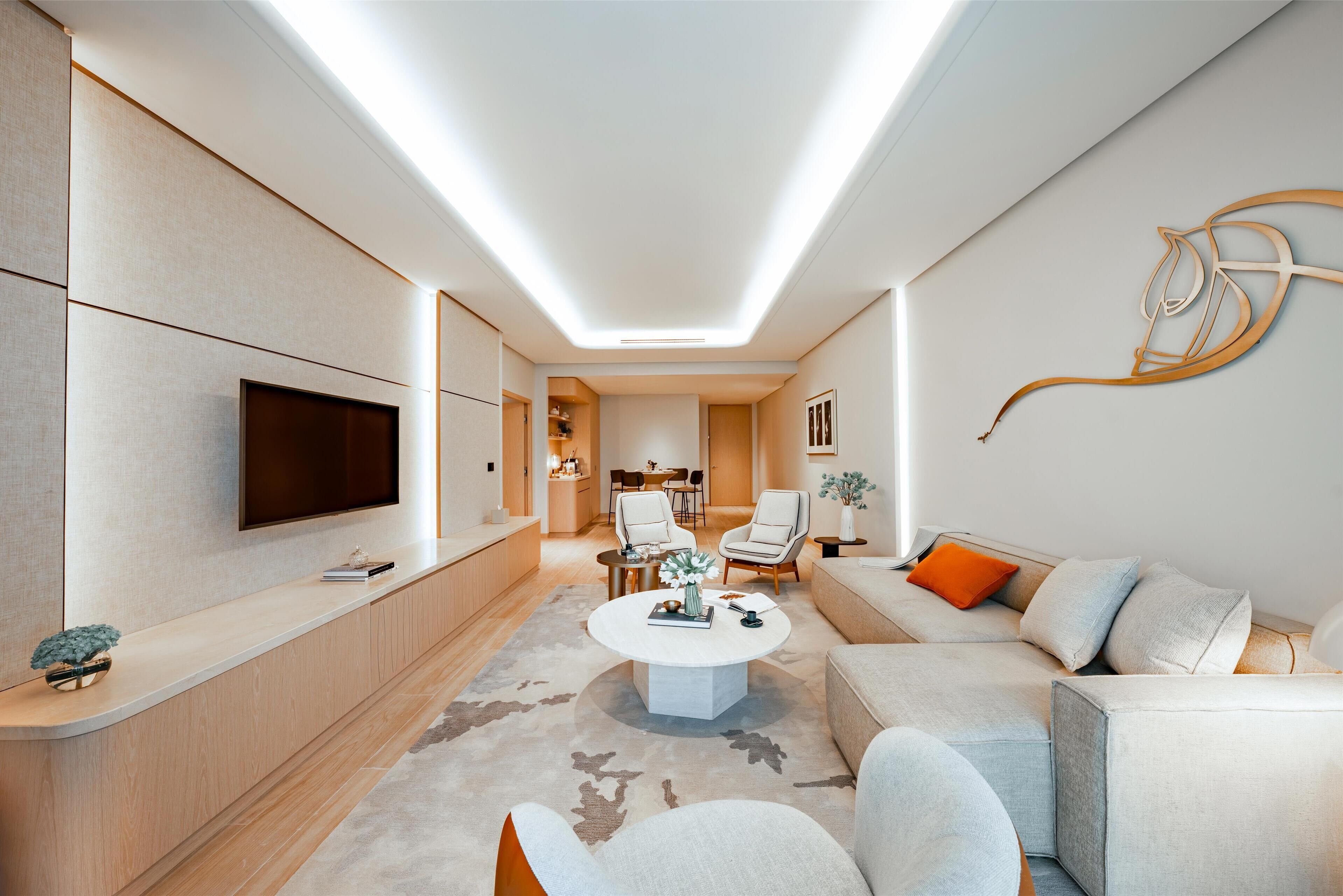 A modern living room with a flat-screen TV, a round coffee table, and a sofa.