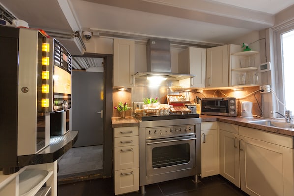 A modern kitchen with stainless steel appliances, white cabinetry, and a built-in oven. - Hotel Hermitage Amsterdam (Amsterdam)