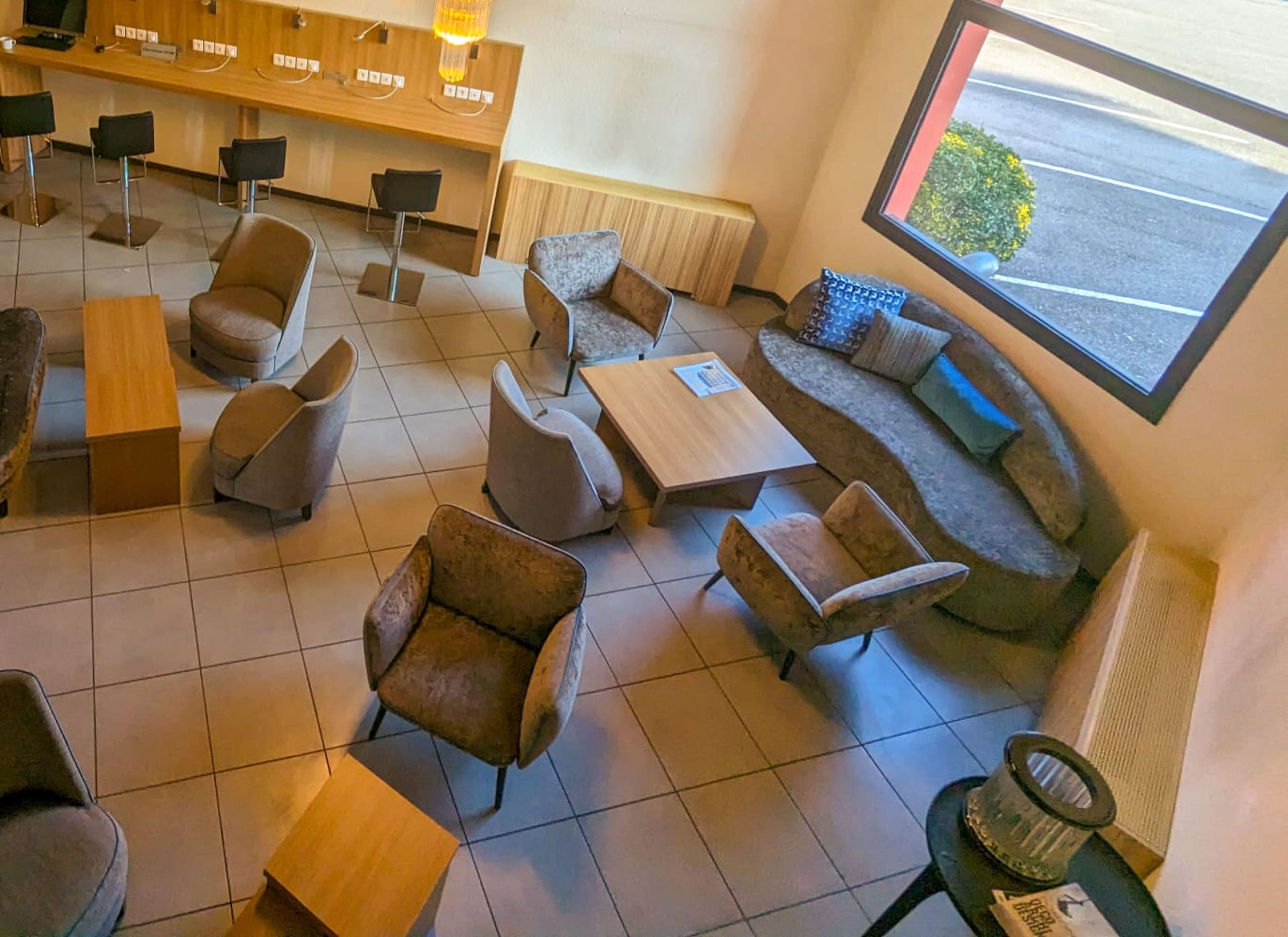 Un espace de détente moderne offrant de nombreuses options d’assises, notamment des canapés, des fauteuils et des tables. On aperçoit un comptoir d’accueil au fond.