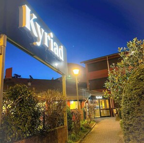 A hotel entrance with a prominent sign reading "Kyriad" and a pathway leading to the building. - Kyriad Lyon Est - Genas Eurexpo (Genas)