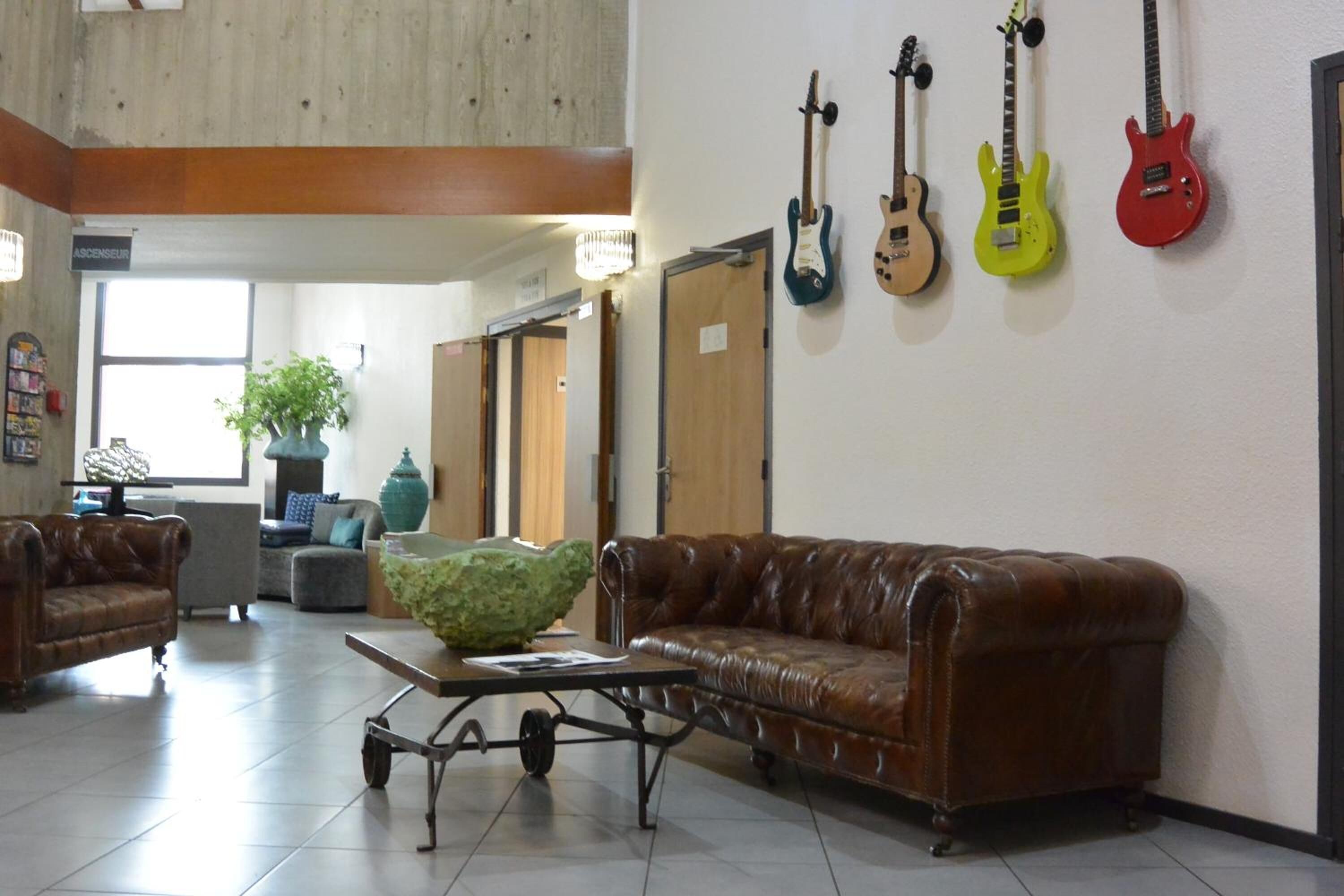 Un vestíbulo con sofás de cuero, una mesa de centro y guitarras colgadas en la pared.