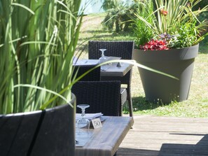 An outdoor dining area with wicker chairs and a table set with a wine glass and a menu. - Kyriad Lyon Est - Genas Eurexpo (Genas)