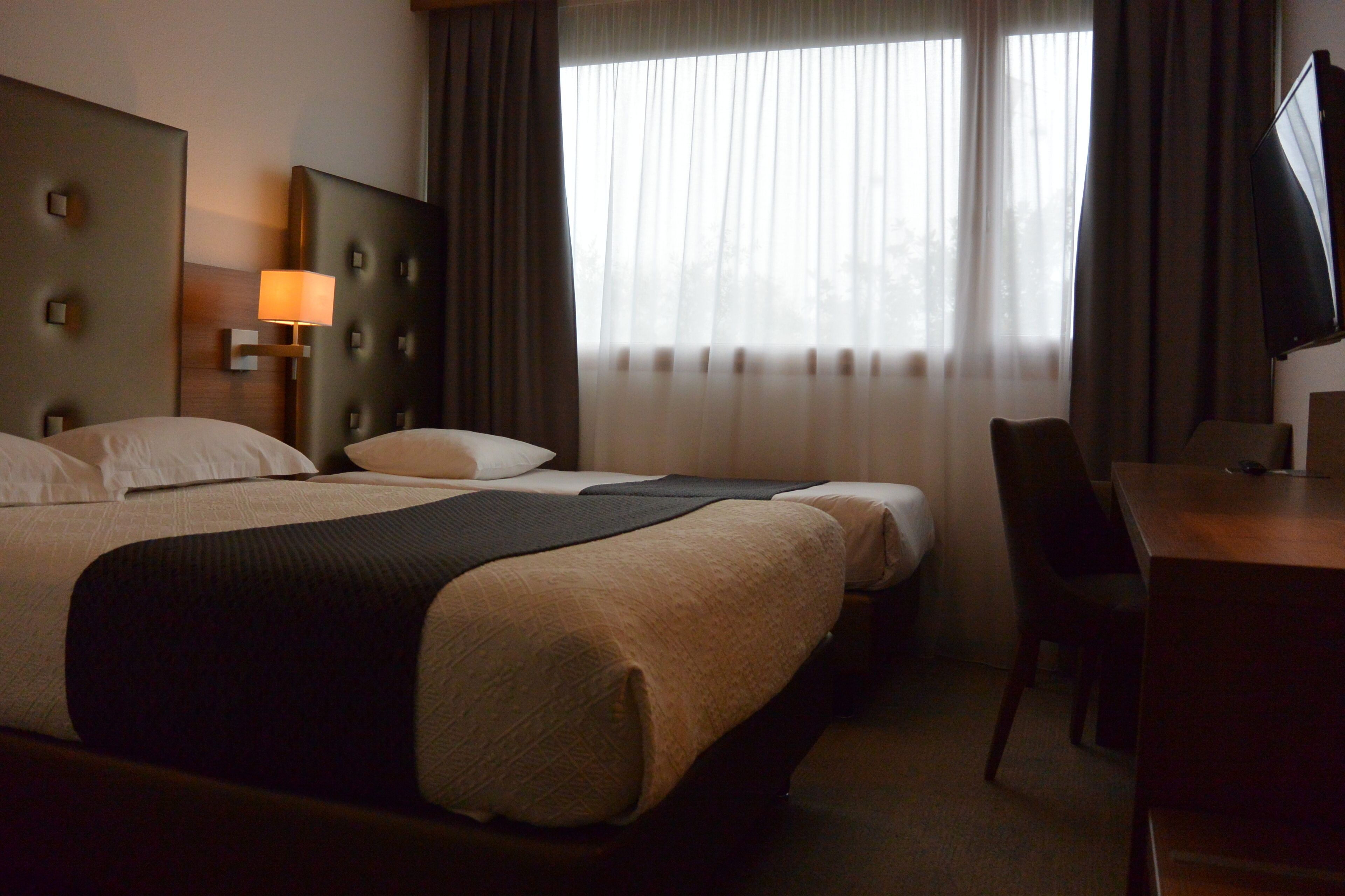 Une chambre d’hôtel avec un grand lit, deux petits lits, un bureau et une télévision.