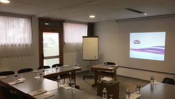 Un salón de conferencias con una larga mesa, sillas, botellas de agua y una pantalla de proyector mostrando el logotipo de BenQ.