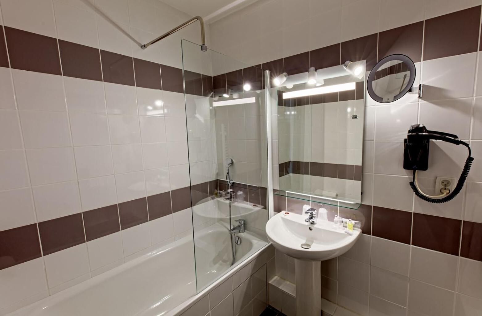 Une salle de bain moderne avec une douche à parois de verre, un lavabo blanc et un miroir doté d'un anneau lumineux.