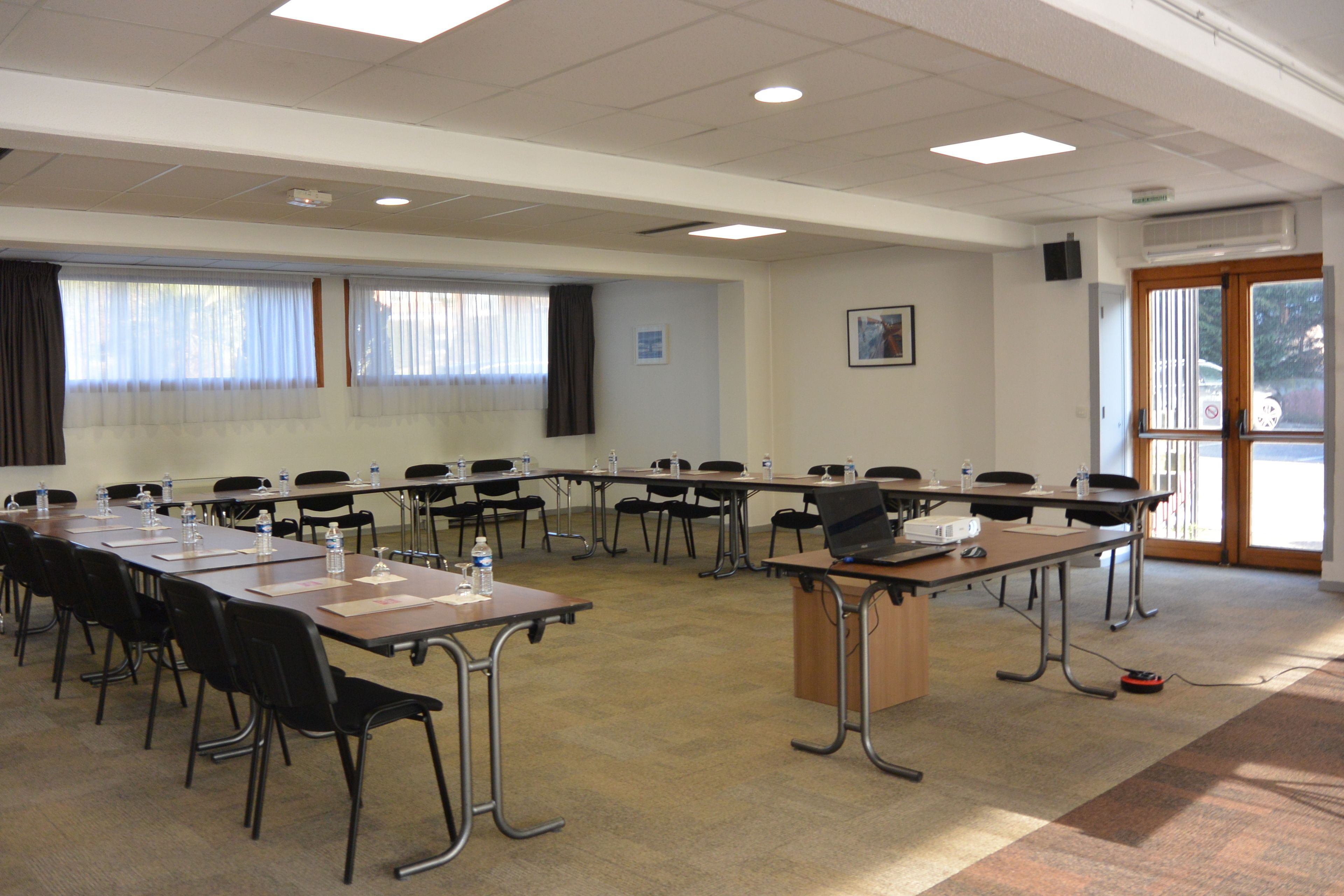 Un salón de conferencias con una larga mesa, sillas y un atril.