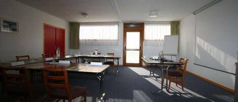 A conference room with a large table, chairs, a whiteboard, and a door.