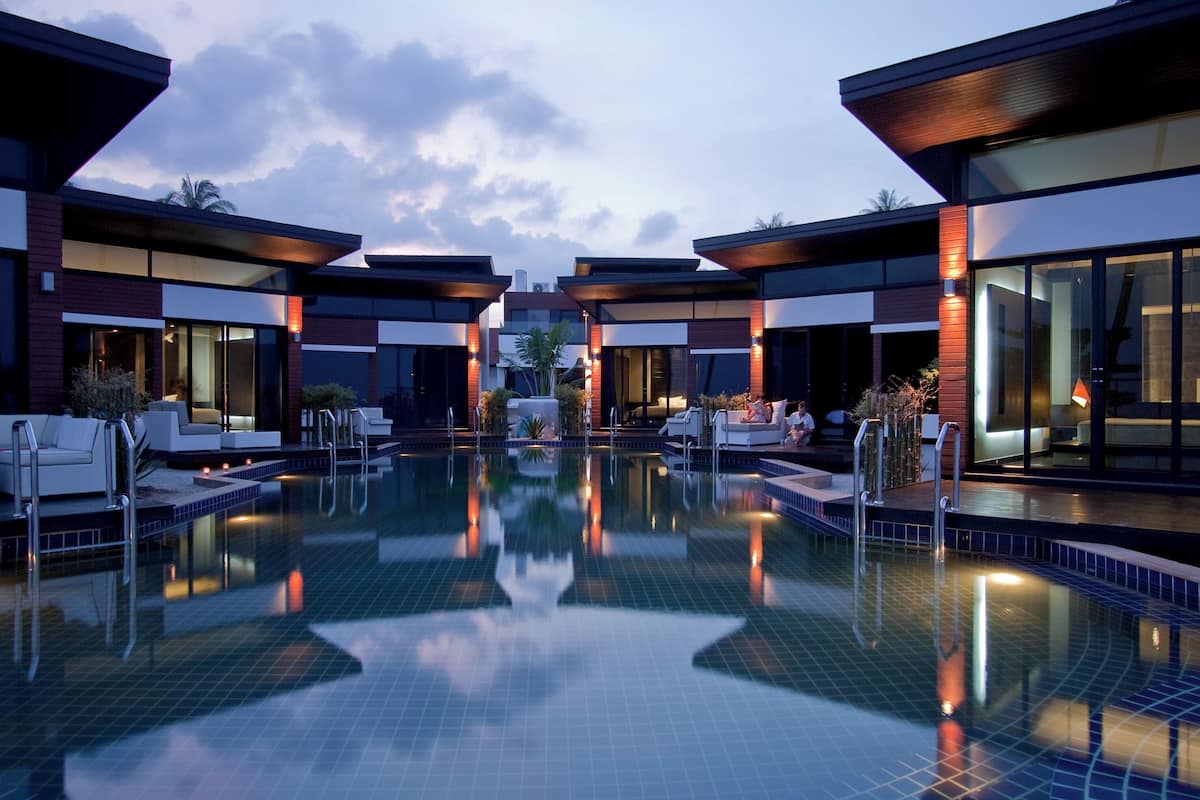 Zona de piscina moderna de hotel con varias tumbonas y una piscina transparente.