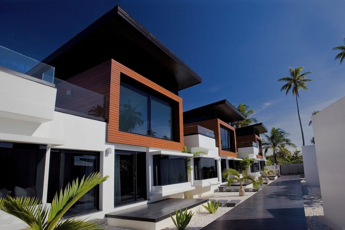 Un moderno resort con arquitectura contemporánea, que cuenta con amplios ventanales y un camino bordeado de palmeras.