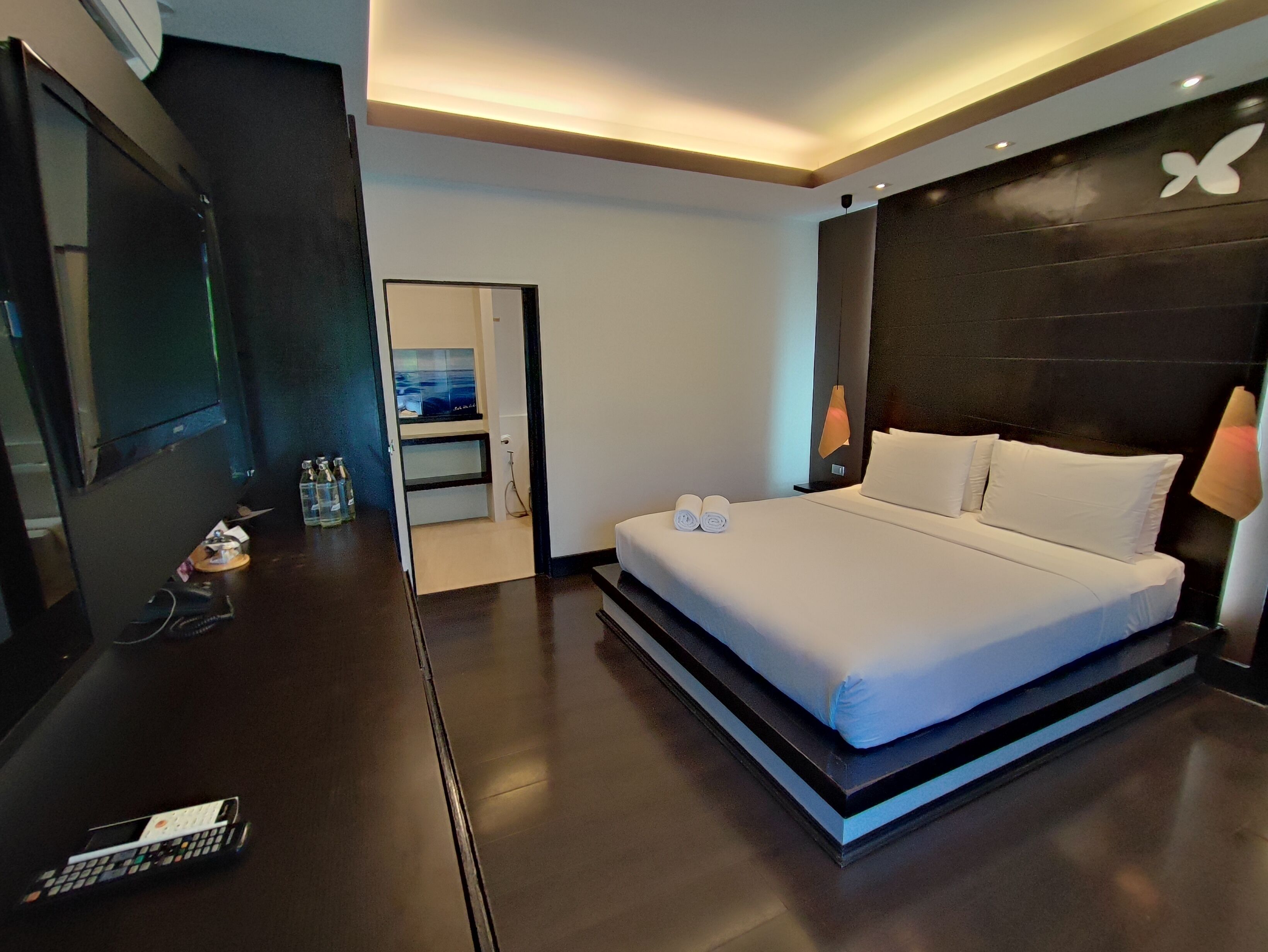 Una habitació d'hotel moderna amb un llit gran, un escriptori amb un telèfon i una televisió.