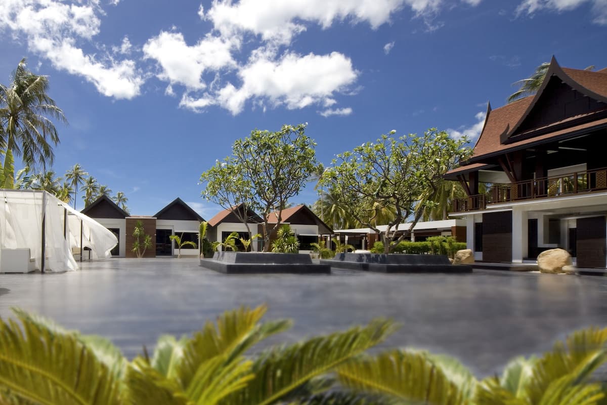 Un resort con varias edificaciones, palmeras y un cielo azul despejado.