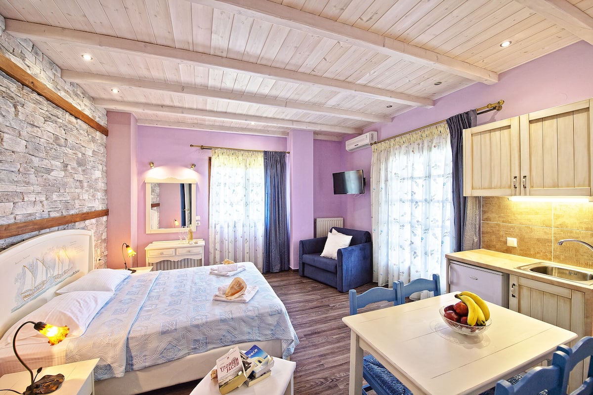 Un dormitorio con cama, mesita de noche y una pequeña mesa de trabajo con un frutero.