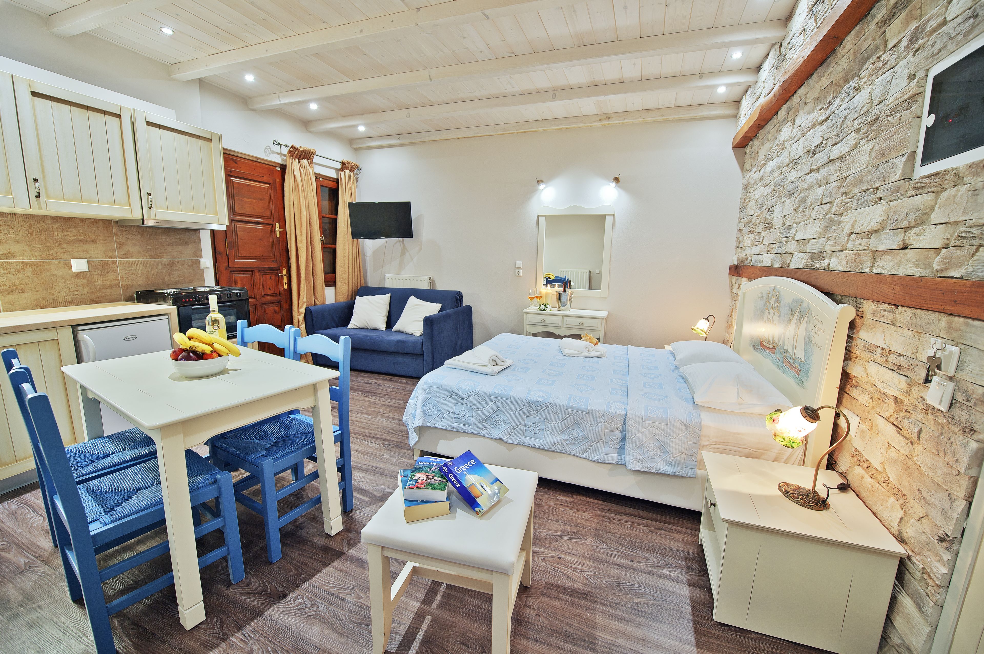 A compact bedroom with a bed, bedside table, lamp, and a small table with books.