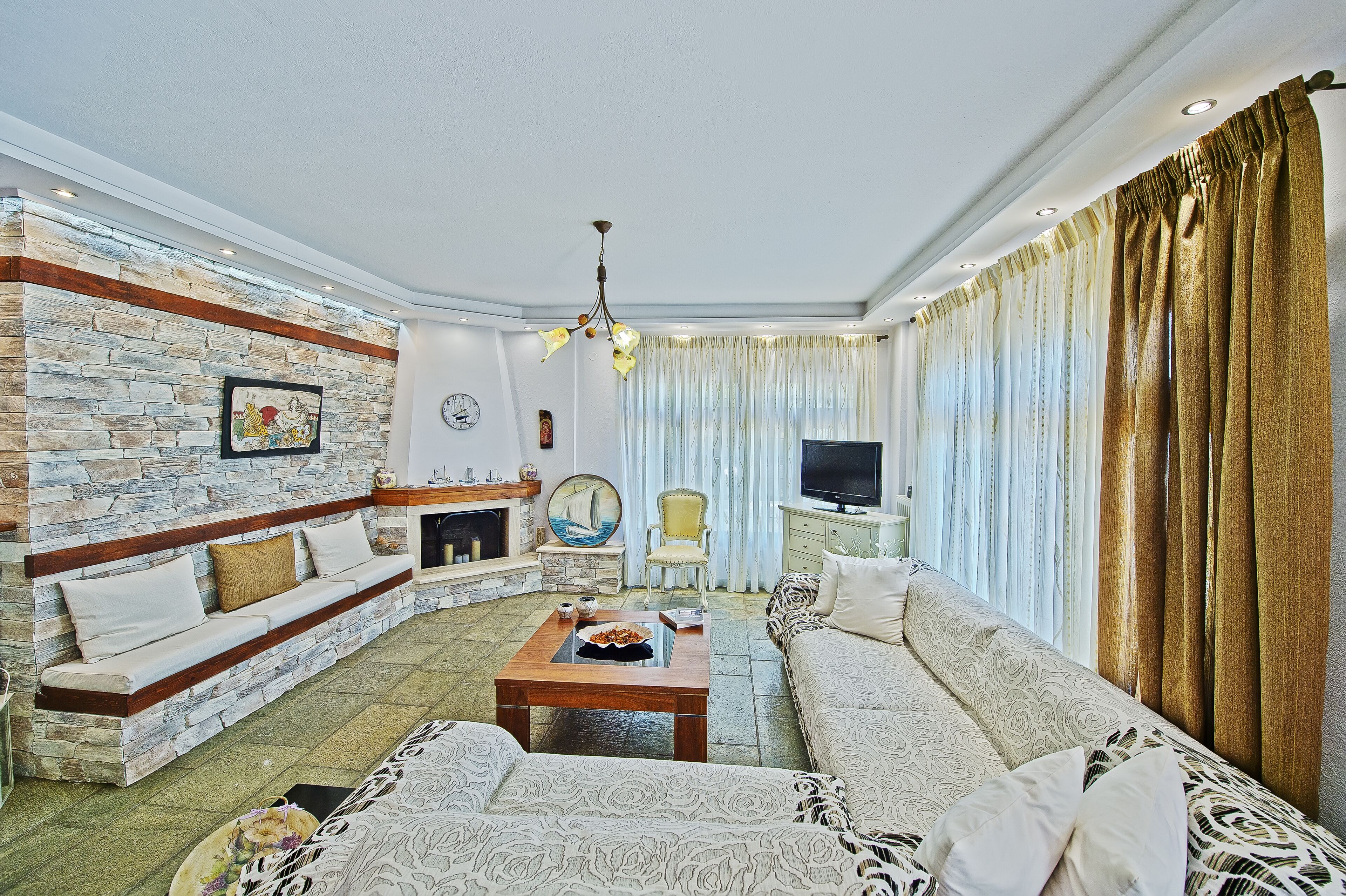 A living room with a stone wall, a sofa, a coffee table, and a television.