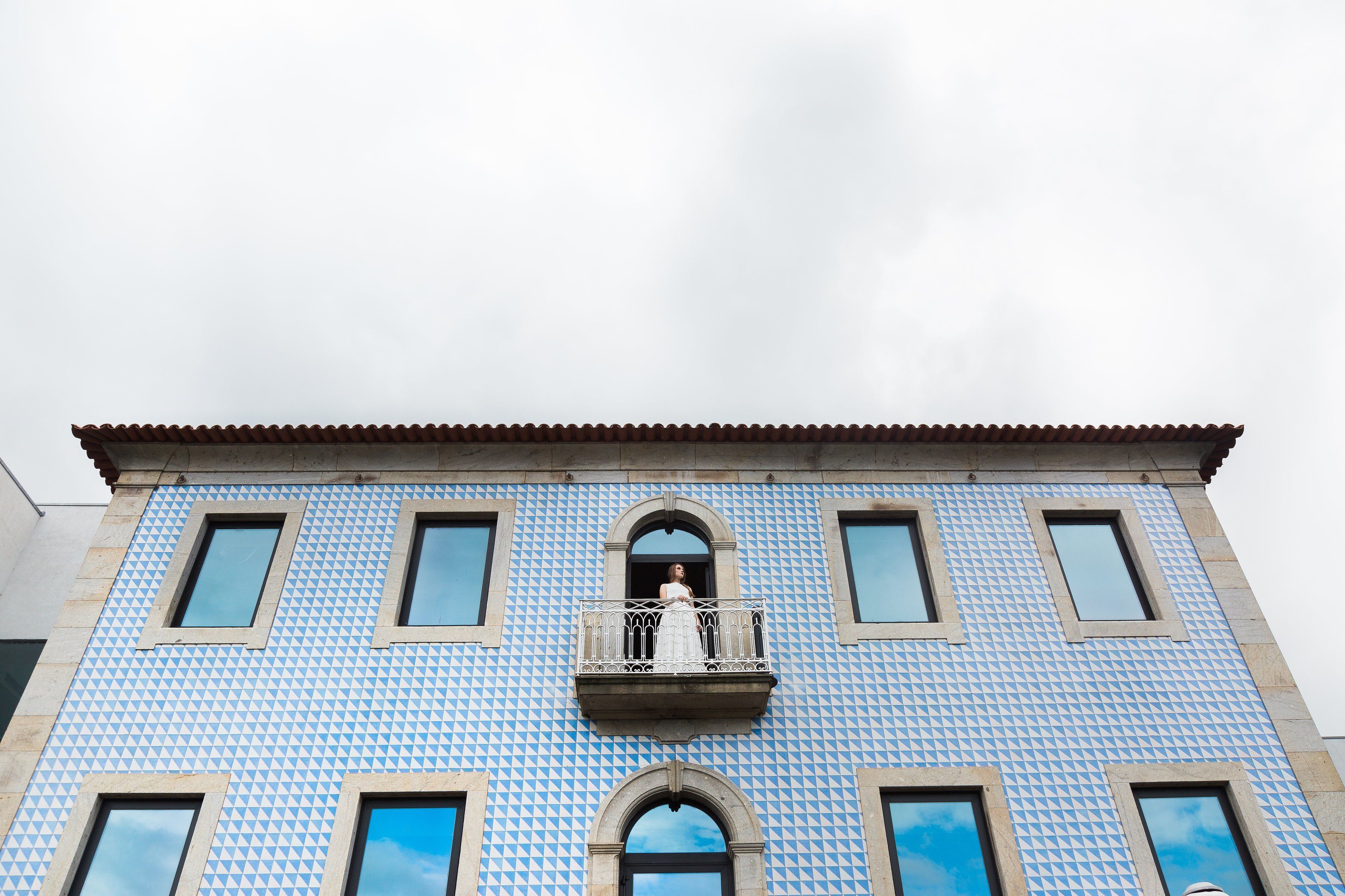 Un edificio con fachada azul estampada y un balcón con barandilla.