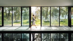 A room with large windows offering a view of an outdoor park with benches and trees. - Douro Palace Hotel Resort and Spa (Baiao)
