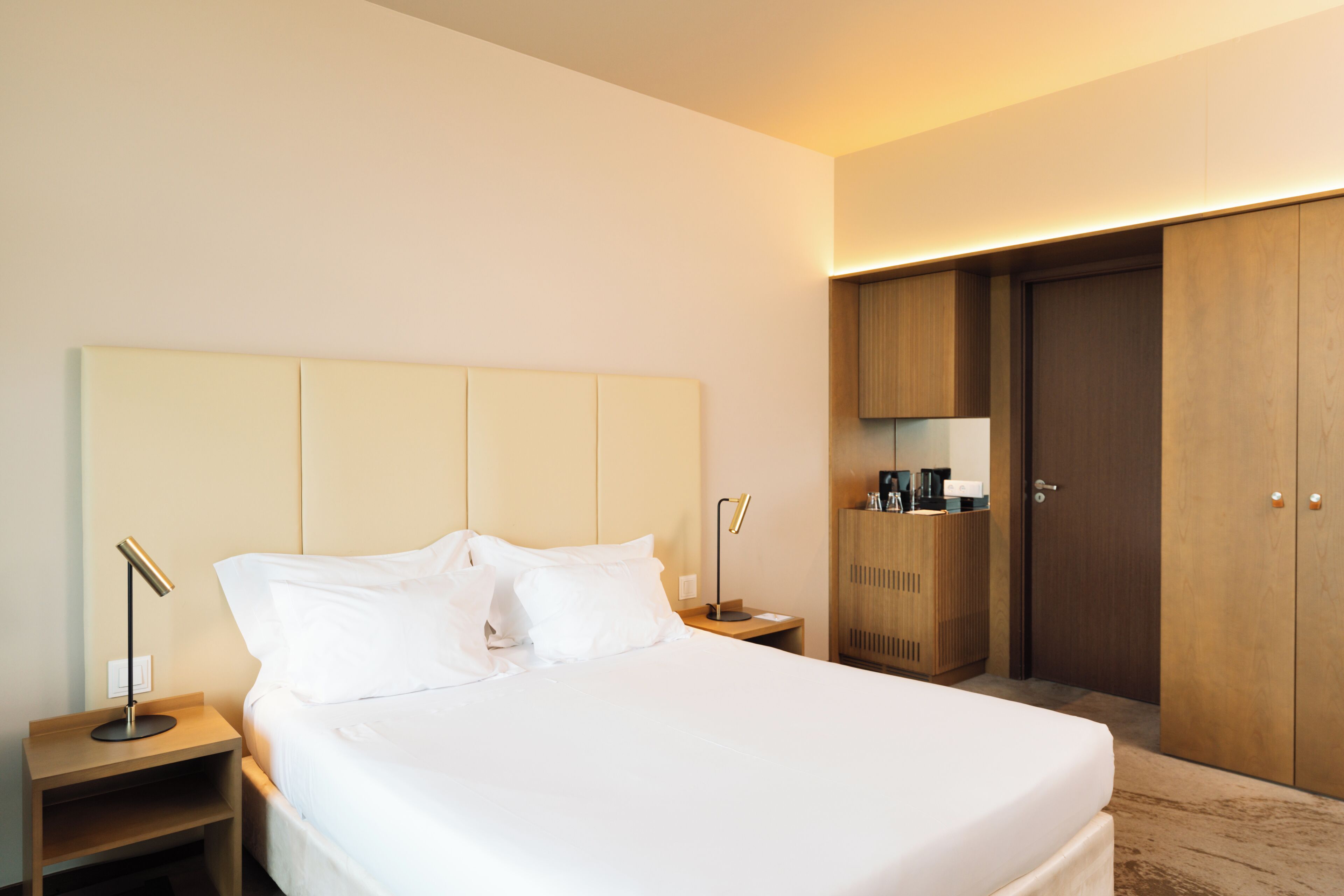 Una habitación de hotel con cama, mesitas de noche, armario y espejo.