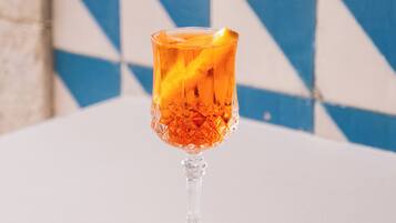 A glass with a drink on a table against a blue and white tiled wall.