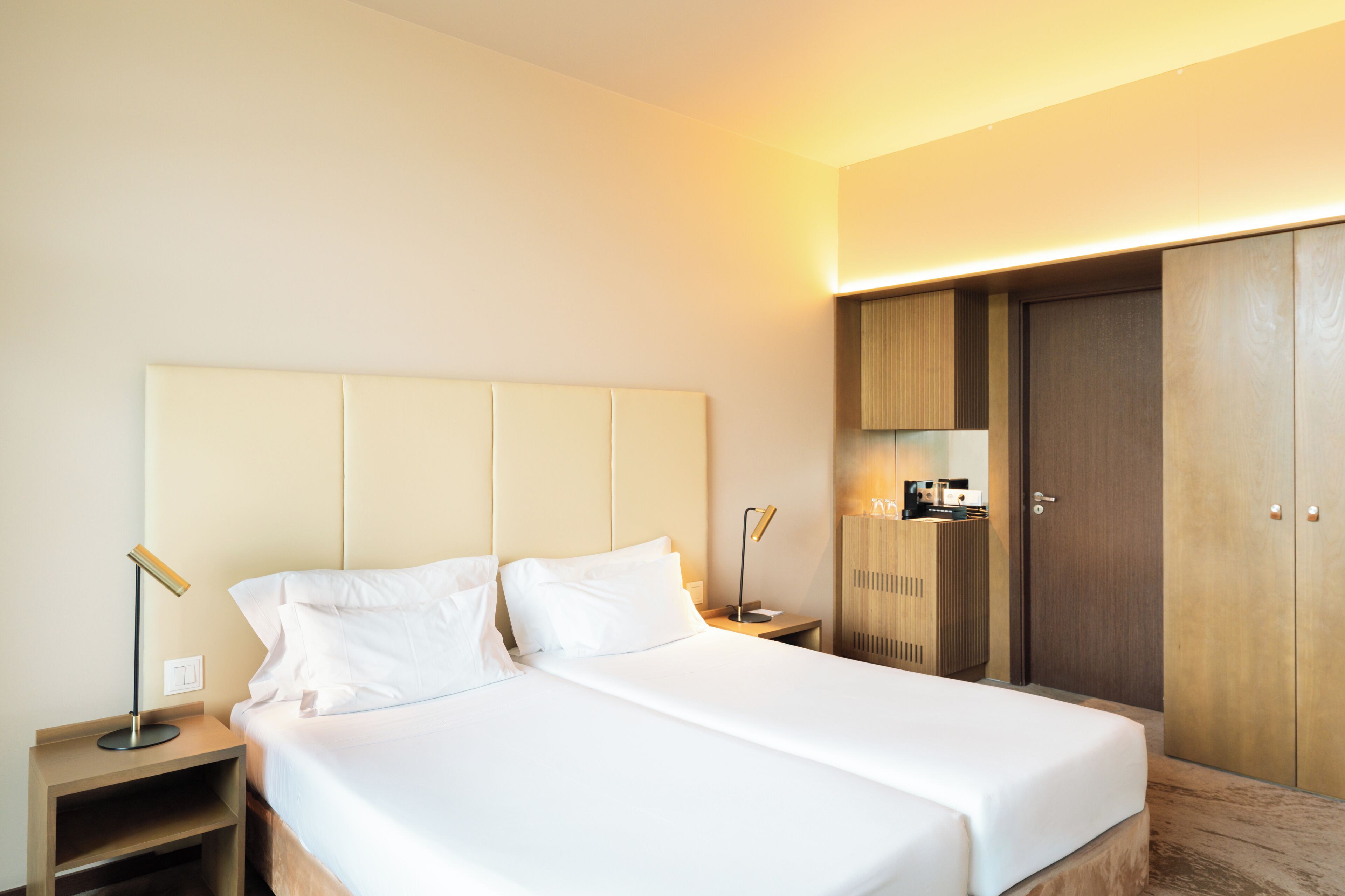 Una habitación de hotel con cama, mesitas de noche, armario y espejo.