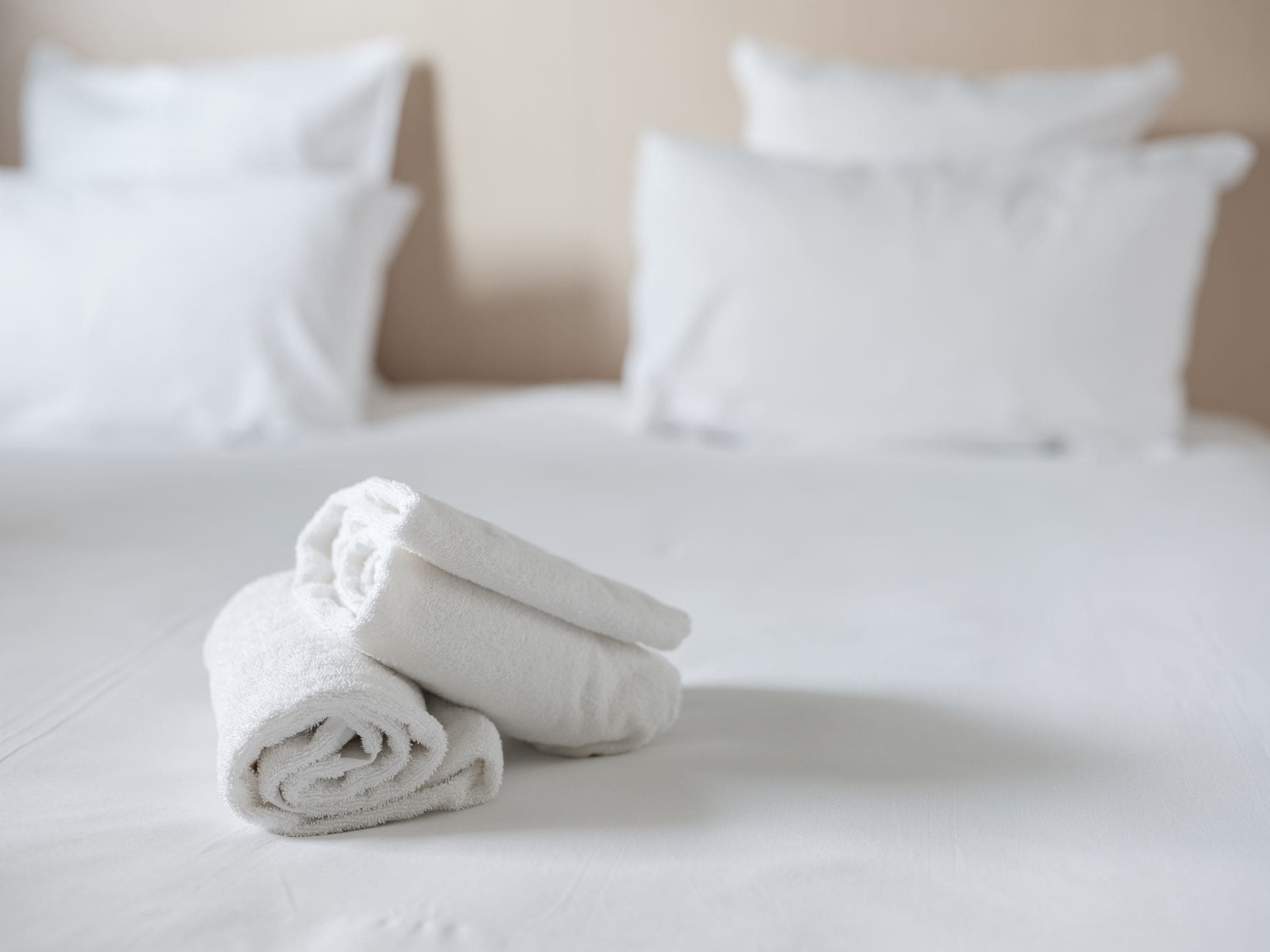 A neatly made bed with white linens and pillows.