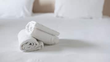 A neatly made bed with white linens and pillows.